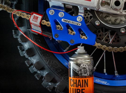 Motorcycle chain with SIK MOTO branding and a can of chain lube in the foreground.