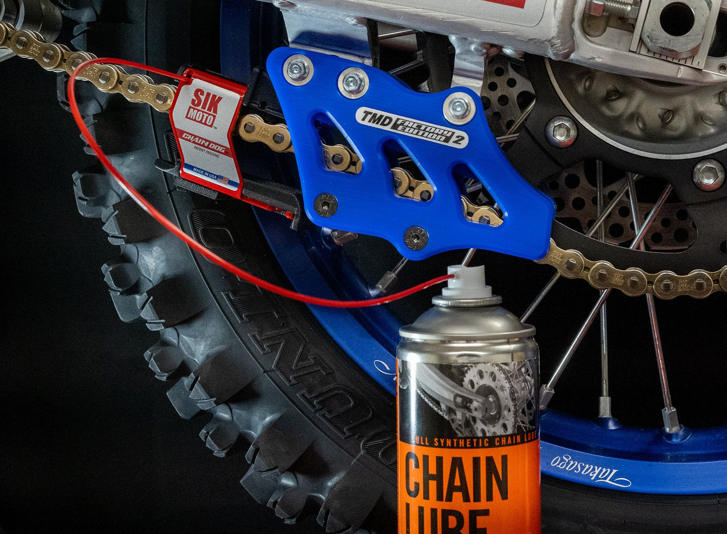 Motorcycle chain with SIK MOTO branding and a can of chain lube in the foreground.