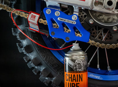 Motorcycle chain with SIK MOTO branding and a can of chain lube in the foreground.